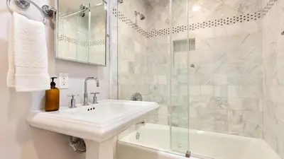 a white bathroom with a sink and a shower at Crystal Cove by AvantStay Gorgeous Charming Newport Home in Newport Beach
