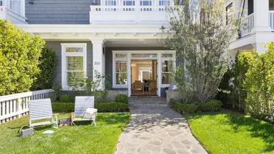 a white house with two chairs in the yard at Crystal Cove by AvantStay Gorgeous Charming Newport Home in Newport Beach