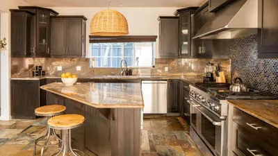 a kitchen with black cabinets and a counter with stools at Sand Castle by AvantStay Beach House on Balboa Peninsula w Patio Hot Tub in Newport Beach