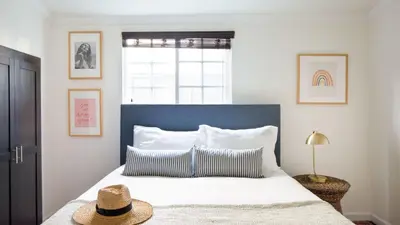 a bedroom with a large bed with a blue headboard at Sand Castle by AvantStay Beach House on Balboa Peninsula w Patio Hot Tub in Newport Beach