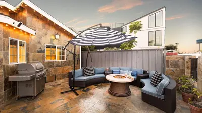 a patio with a table and chairs and an umbrella at Sand Castle by AvantStay Beach House on Balboa Peninsula w Patio Hot Tub in Newport Beach