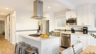 a kitchen with white cabinets and a counter top at Mission Point 1 by AvantStay San Diego Beach House w Huge Patio Fire Pit Walk to Beach in San Diego