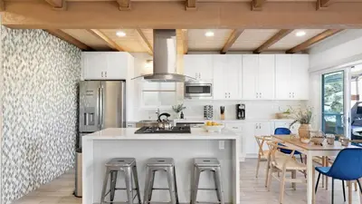 a kitchen with white cabinets and a table with chairs at Mission Point 2 by AvantStay Mission Beach Home w Large Balcony Steps to Beach in San Diego