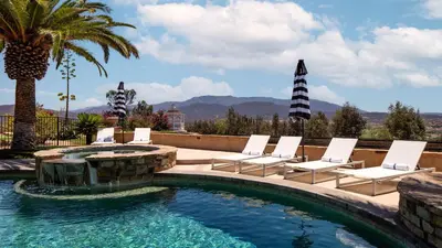 a swimming pool with lounge chairs and a palm tree at Sangiovese By AvantStay Spectacular Estate w Pool Hot Tub Putting Green in Temecula