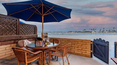 a table and chairs with an umbrella on a patio at Bay View II by AvantStay Ocean View Mission Beach Home on the Sand in San Diego