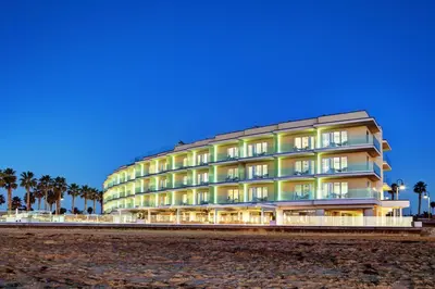 a building on the beach with palm trees at Pier South Resort, Autograph Collection in Imperial Beach