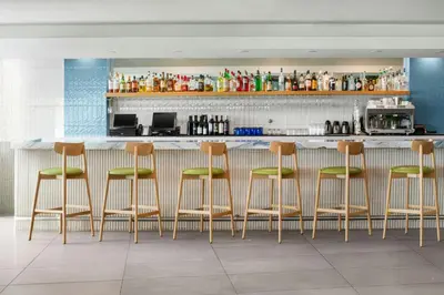 a bar with four stools in front of a counter at Pier South Resort, Autograph Collection in Imperial Beach