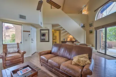 a living room with a leather couch and a staircase at Borrego Springs Retreat with Grill and Patio! in Borrego Springs