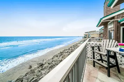 a balcony with a table and a chair and the ocean at Whitewater Village Charm in Oceanside