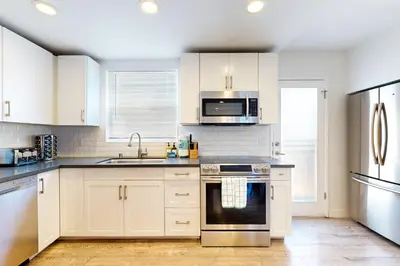 a kitchen with white cabinets and stainless steel appliances at La Jolla Beach Retreat in San Diego