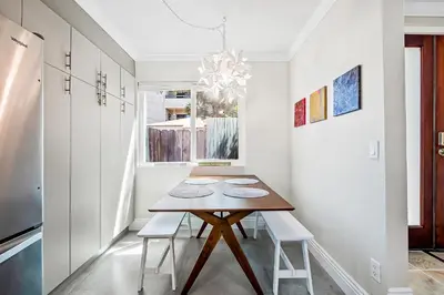 a dining room with a wooden table and white walls at Sunsoak Shack in San Diego