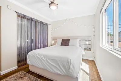 a white bedroom with a large bed and a window at Sunsoak Shack in San Diego