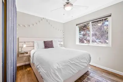 a white bedroom with a bed and a window at Sunsoak Shack in San Diego