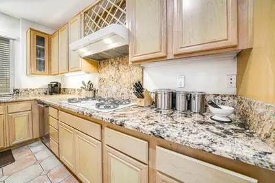 a kitchen with wooden cabinets and a counter top at Ocean Pointe Getaway - 30-Night Minimum in Carlsbad