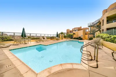 a large swimming pool with chairs and a table at Ocean Pointe Getaway - 30-Night Minimum in Carlsbad