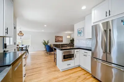 a kitchen with white cabinets and a stainless steel refrigerator at The Little Crab Shack in Dana Point