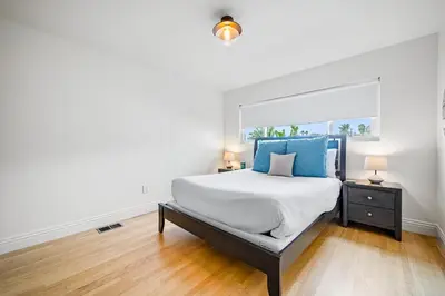 a bedroom with a large bed with blue pillows at The Little Crab Shack in Dana Point