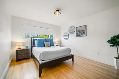 a white bedroom with a bed and a window at The Little Crab Shack in Dana Point