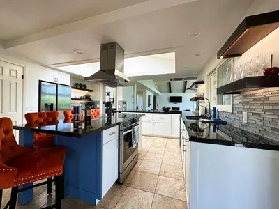 a large kitchen with white cabinets and a blue island at Hilltop Villa, Pool Oasis, Pickleball Court, Avocado Grove, Views in Fallbrook