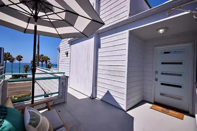 a balcony with an open door and an umbrella at Fantastic Ocean View Remodeled All New Furnishings Pet Friendly AC in Oceanside