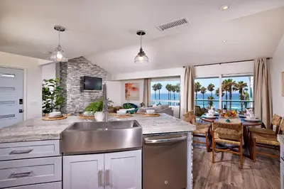 a kitchen with a sink and a living room at Fantastic Ocean View Remodeled All New Furnishings Pet Friendly AC in Oceanside