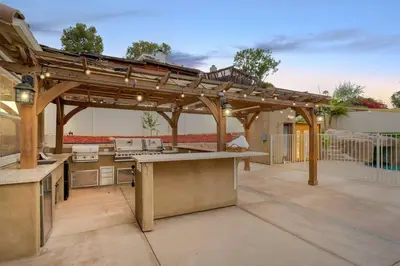 an outdoor kitchen with a wooden pergola at San Diego Luxury Oasis in Spring Valley