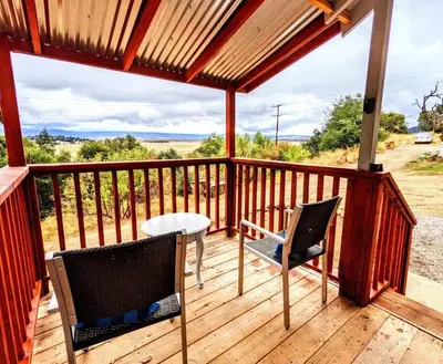a wooden deck with two chairs and a table on it at The Luminous Lodge-Remodeled Cabin W/ Valley Views in Santa Ysabel