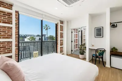 a bedroom with a white bed and a balcony at The Brick Boutique Hotel in Oceanside