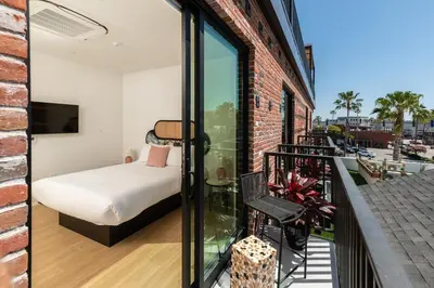 a room with a bed and a balcony with a bedroom at The Brick Boutique Hotel in Oceanside