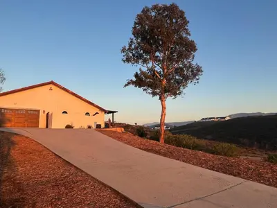 a house with a tree on the side of a road at Winery Getaway with Spa and Amazing Hilltop View in Temecula