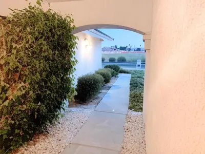 a walkway through a building with a hedge at Stallion Crest Suite with TV and private bathroom in Hemet