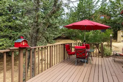 a deck with two chairs and a table with an umbrella at Historical Cabin in Julian Pet's okay! in Julian