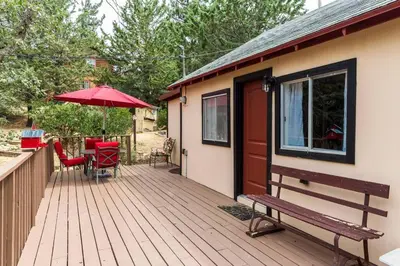 a house with a deck with a bench and an umbrella at Historical Cabin in Julian Pet's okay! in Julian