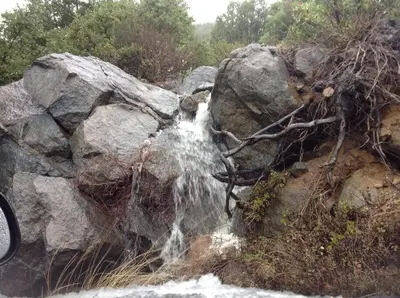 a waterfall on the side of a rock pile at A LIVING CANVAS Amazing Lake View Custom Home in Julian
