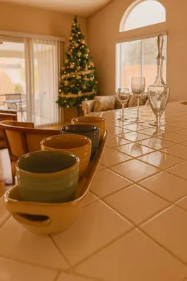 a table with bowls and wine glasses and a christmas tree at Sundance Retreat in Hemet