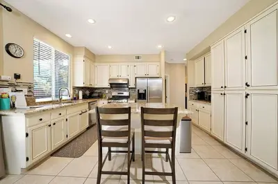 a kitchen with white cabinets and a table with two chairs at Pool-BBQ-View-Balcony-Fireplace-King-Garage-WD in Lake Elsinore