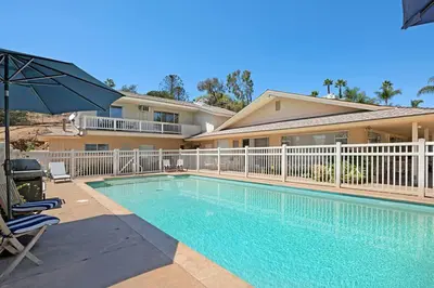 a swimming pool in front of a house with an umbrella at Charming 2 Room La Mesa Casita w/ Pool, BBQ & Yard in La Mesa