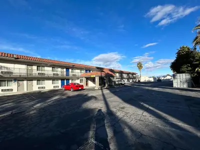 a red car parked in front of a building at Studio 6 Hemet, CA in Hemet