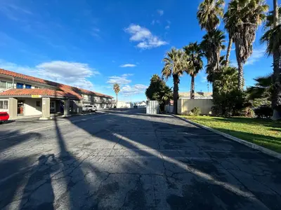 an empty street with palm trees and a building at Studio 6 Hemet, CA in Hemet