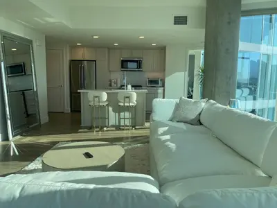 a living room with a white couch and a kitchen at Luxury Designer Suite with Rooftop Pool, Gym in San Diego