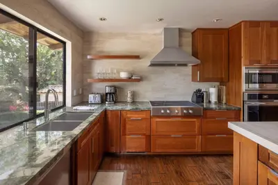 a kitchen with wooden cabinets and a large window at Solana Beach House! Minutes to Dog Beach & Cedros in Solana Beach