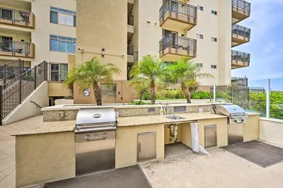 a kitchen with a sink and a grill in front of a building at Breezy Oceanside Condo Less Than half Mi to Beach! in Oceanside