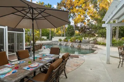 a patio with a table with an umbrella and a pool at Mi Casa es Su Casa! (My Home is Your Home!) in Vista