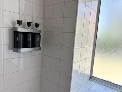 a white tiled shower stall with a bottle of wine at Meadow Harvest Suite with TV and private bathroom in Hemet