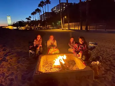 a group of women sitting around a fire on the beach at Blue Whale Inn San Clemente Retreat Unit E in San Clemente