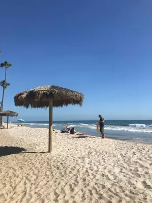 a beach with a straw umbrella and people on the beach at Blue Whale Inn San Clemente Retreat Unit E in San Clemente