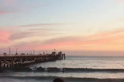 a beach with a pier and people in the water at Blue Whale Inn San Clemente Charmer Unit A in San Clemente