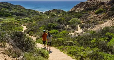 two people walking down a trail near the ocean at Gaslamp 2BR Suite Free Parking Convention Walk in San Diego
