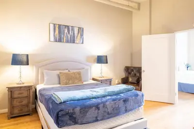 a bedroom with a bed and two lamps and a chair at Top Floor Walk to Conv Center Free Parking in San Diego
