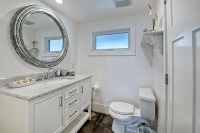 a white bathroom with a toilet and a mirror at Luxury Ocean Views & Steps To The Sand - Tower 36 Lower Condo Unit in Carlsbad